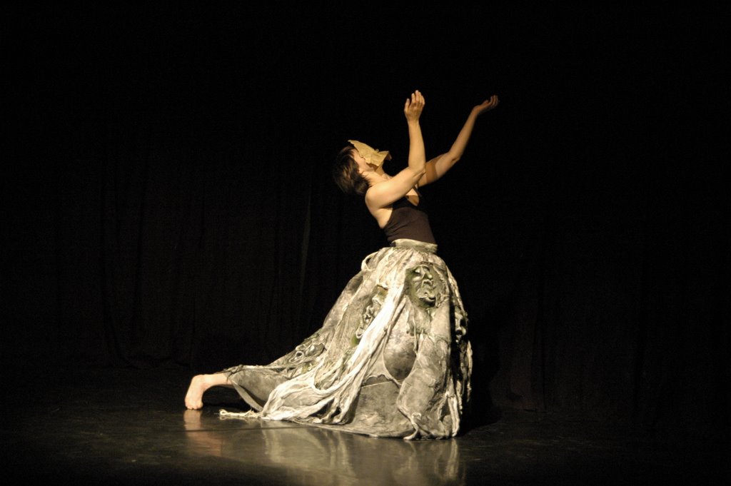 dancer moving with a heavy skirt made of masks with an extra long leg poking from its bottom edge